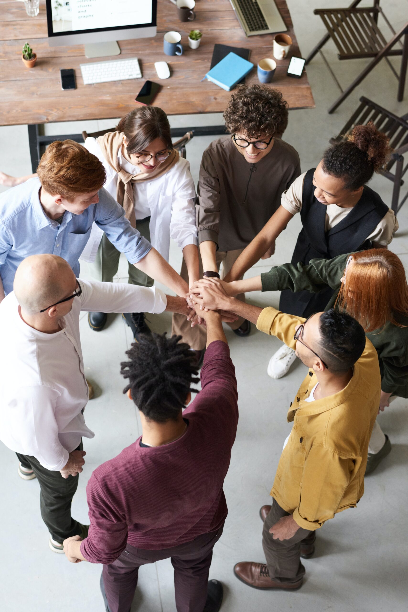 team of 8 people standing in a circle reaching out a hand to connect with others in the centre