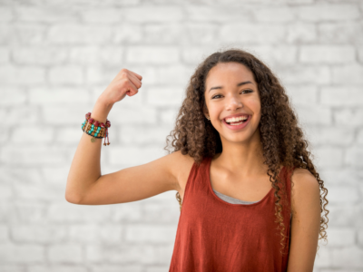Photo of a smiling person striking the strong pose for International Women's Day 2025 Accelerate Action